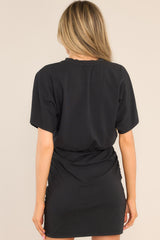 Back view of this dress that features a crew neckline, an elastic waistband, ruching down the sides, and wide sleeves.