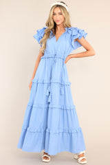 This blue dress features a v-neckline with a self-tie closure, ruffled flutter sleeves, a drawstring waistband, and a long, flowy skirt.