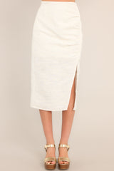 Full front view of this skirt that features a high waisted design, a discrete side zipper, a thick exposed side seam with ruching, and a side slit.