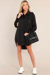 This black mini dress features a collared neckline, functional buttons down the front, buttoned cuffed long sleeves, and a satin-like material.