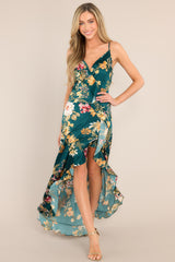 Front view of this emerald floral dress that features a v-neckline, adjustable straps, an open back, a functional side zipper, a faux wrap design, and a high slit.