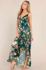 This emerald floral dress features a v-neckline, adjustable straps, an open back, a functional side zipper, a faux wrap design, and a high slit.