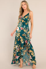 Emerald floral dress featuring a v-neckline, adjustable straps, an open back, a faux wrap design, and a high slit up the side.