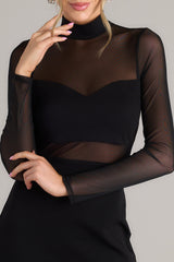 Close up view of this dress that features a high neckline, a discrete zipper down the back, meshing in the chest, back, & waist, a bodycon style fit, and fully meshed long sleeves.