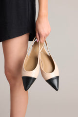 These beige and black flats feature a pointed toe, a color block design, and non adjustable strap.