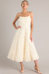 This ivory midi dress features tulle ruffles throughout, and thin shoulder straps.