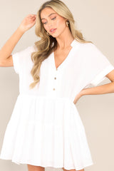 This white mini dress features a collared v-neckline, a functional button front, a two tier design, and cuffed short sleeves.
