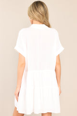 Detailed rear shot of a white mini dress featuring a collared v-neckline, a functional button front, a two tier design, and cuffed short sleeves.