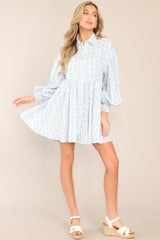 Full body view of this blue print dress featuring a collared neckline, functional buttons down the front, long sleeves with smocked cuffs, and a flowy, relaxed fit throughout.