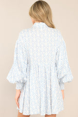 Rear shot of this blue print dress featuring a collared neckline, functional buttons down the front, long sleeves with smocked cuffs, and a flowy, relaxed fit throughout.