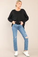 This black sweater features a round, ribbed neckline, a seam going down the center, and a ribbed hem and cuffs.