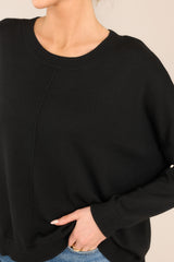 Close up view of this sweater that features a round, ribbed neckline, a seam going down the center, and a ribbed hem and cuffs.