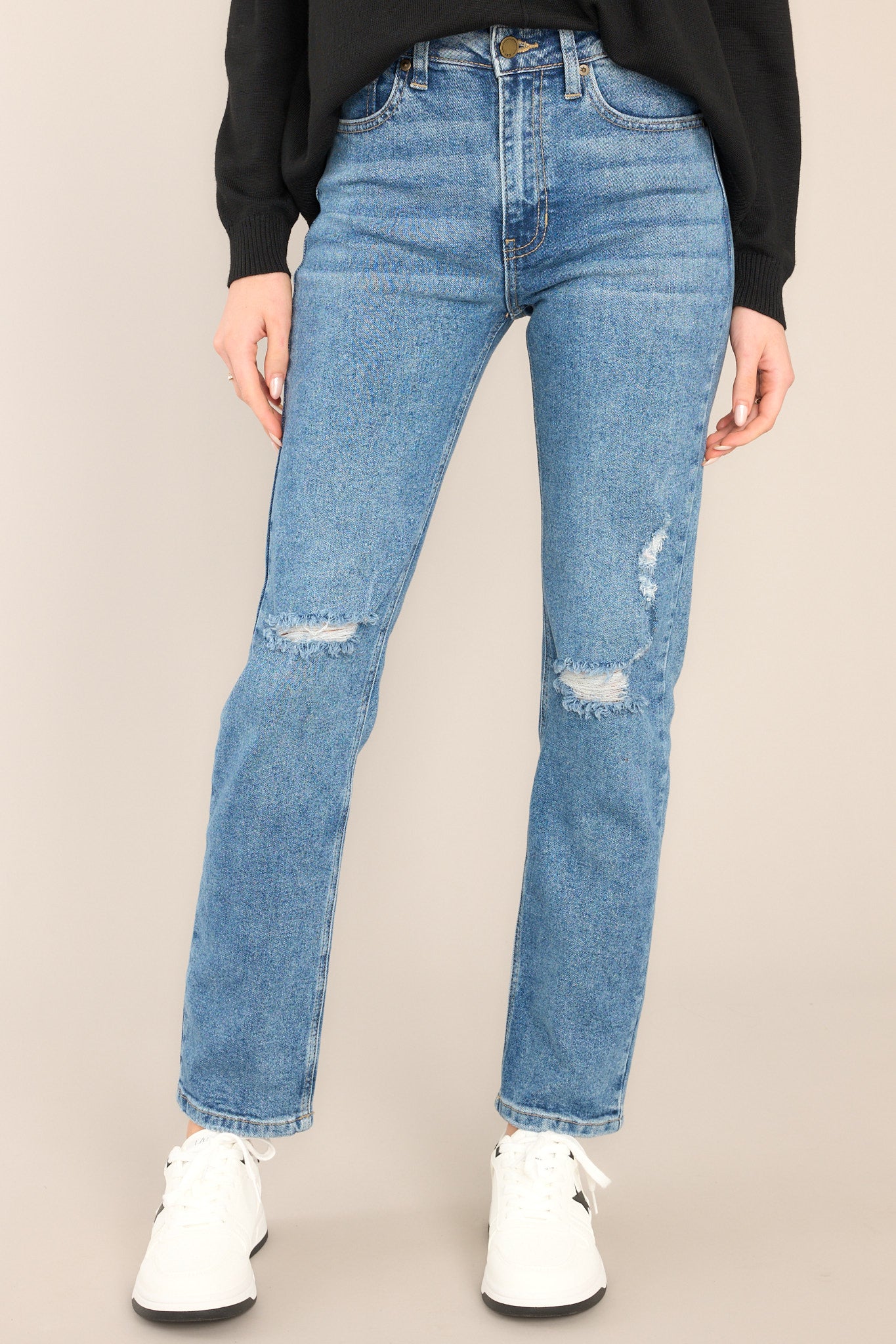 Front view of jeans that feature a high rise, a belt loops, a zipper and button closure, distressing at the knee and a clean bottom hem. 