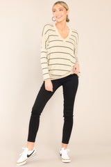 This taupe and black top features a v-neckline, mid-length sleeves, striped design, and an oversized fit.