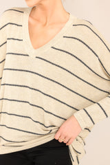 Close up view of this top that features a v-neckline, mid-length sleeves, striped design, and an oversized fit.
