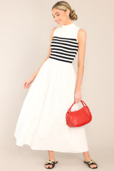 This black and white dress features a high neckline, a striped sweater bodice, and a flowy skirt.
