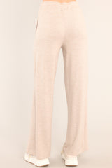 Back view of these tan lounge pants that feature an elastic waistband with a self-tie drawstring, pockets, and a wide leg.