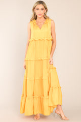 Relaxed front view of dress that features a ruffled v-neckline with a self-tie closure, a sleeveless design, and a flowy skirt with subtle ruffle detailing throughout.