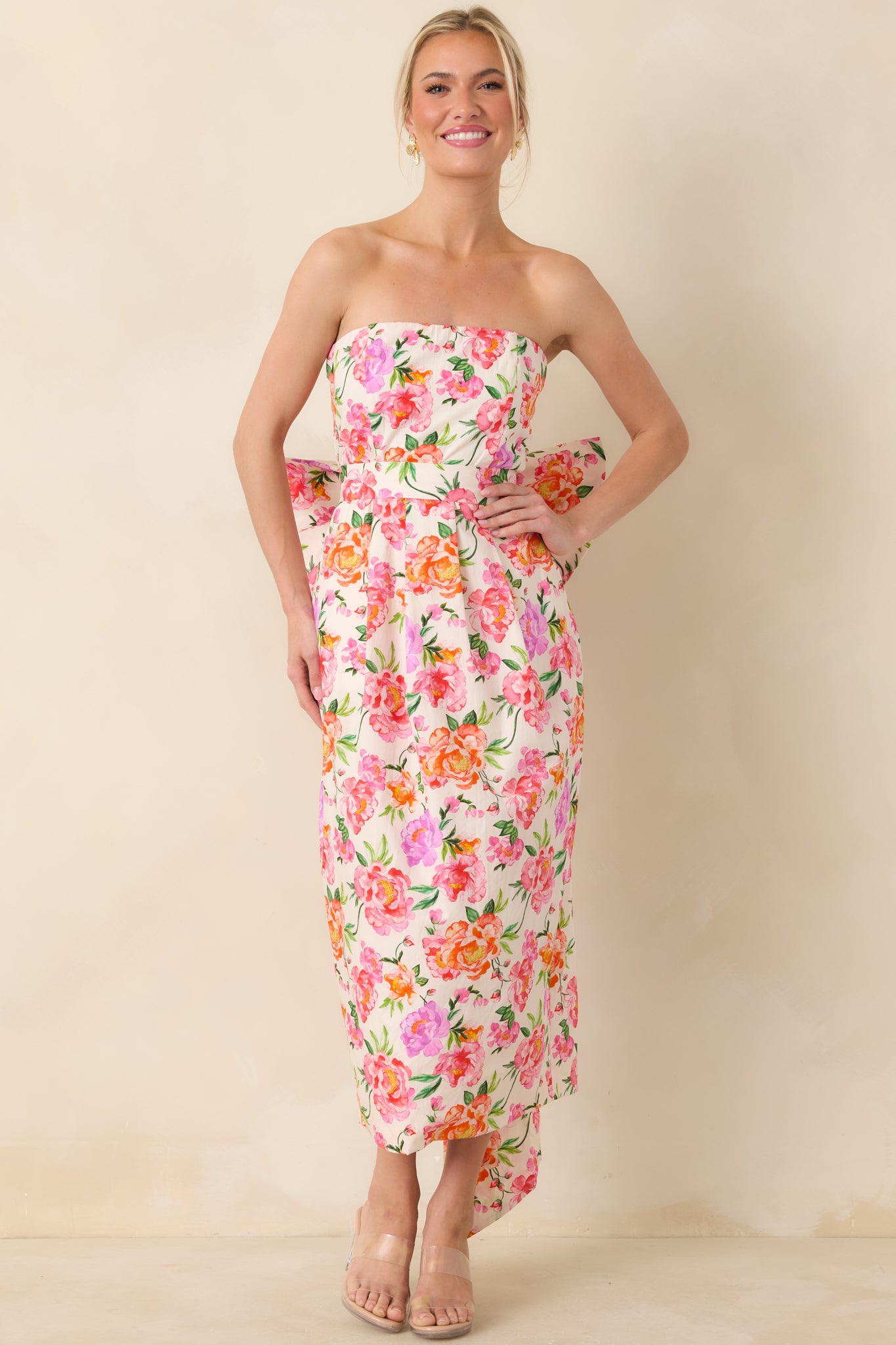 Strapless cotton midi dress in vibrant pink with multi floral print, fitted bodice, and a streamlined skirt creating an elegant silhouette.