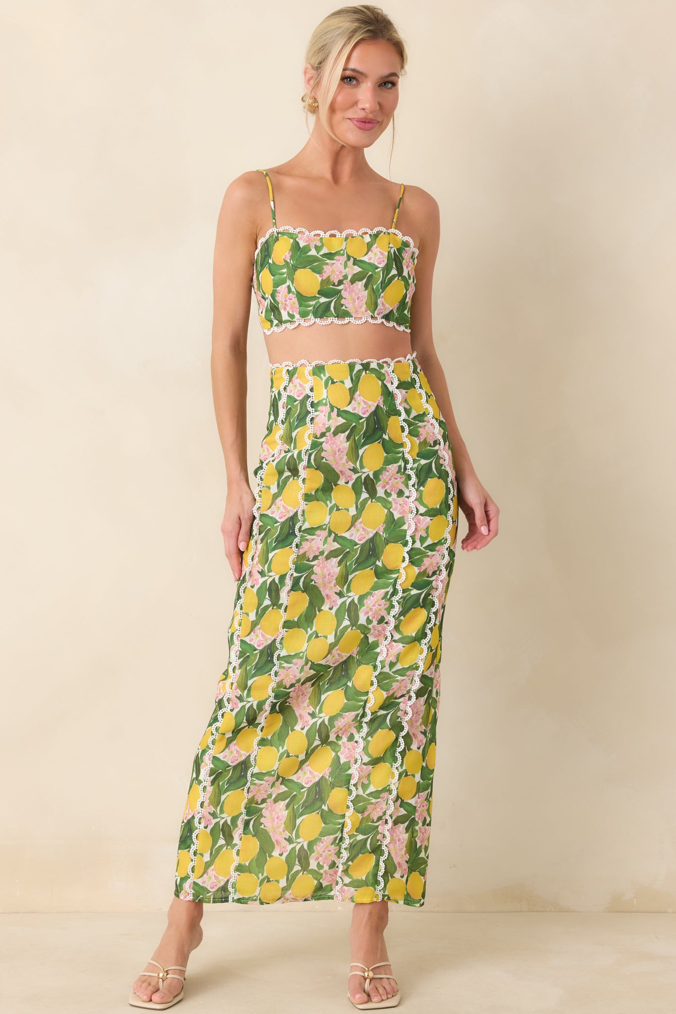 Yellow multi cropped camisole with a fitted bodice, straight scalloped lace-trim neckline, and adjustable spaghetti straps in a lemon blossom print.