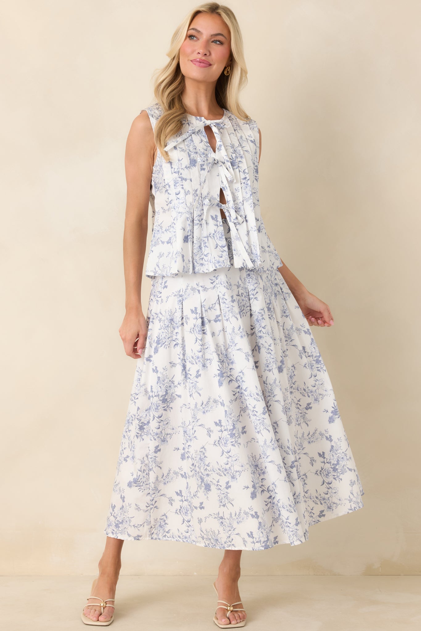 Sleeveless cotton top in ivory with a blue floral toile print, featuring a relaxed swing silhouette and front tie closure.