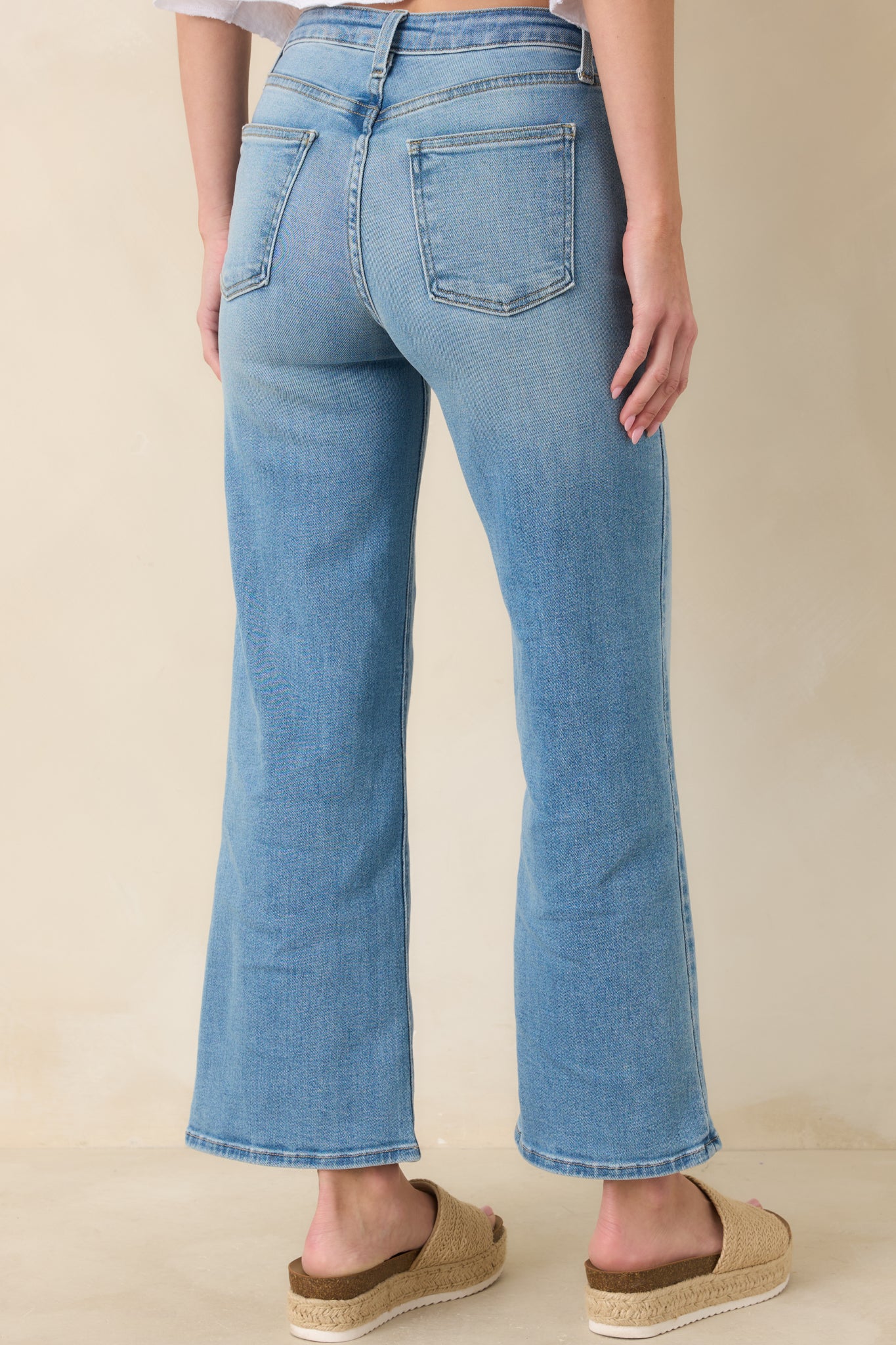 Rear view of light wash jeans displaying back pockets, high-rise waistband, and slightly cropped wide-leg fit