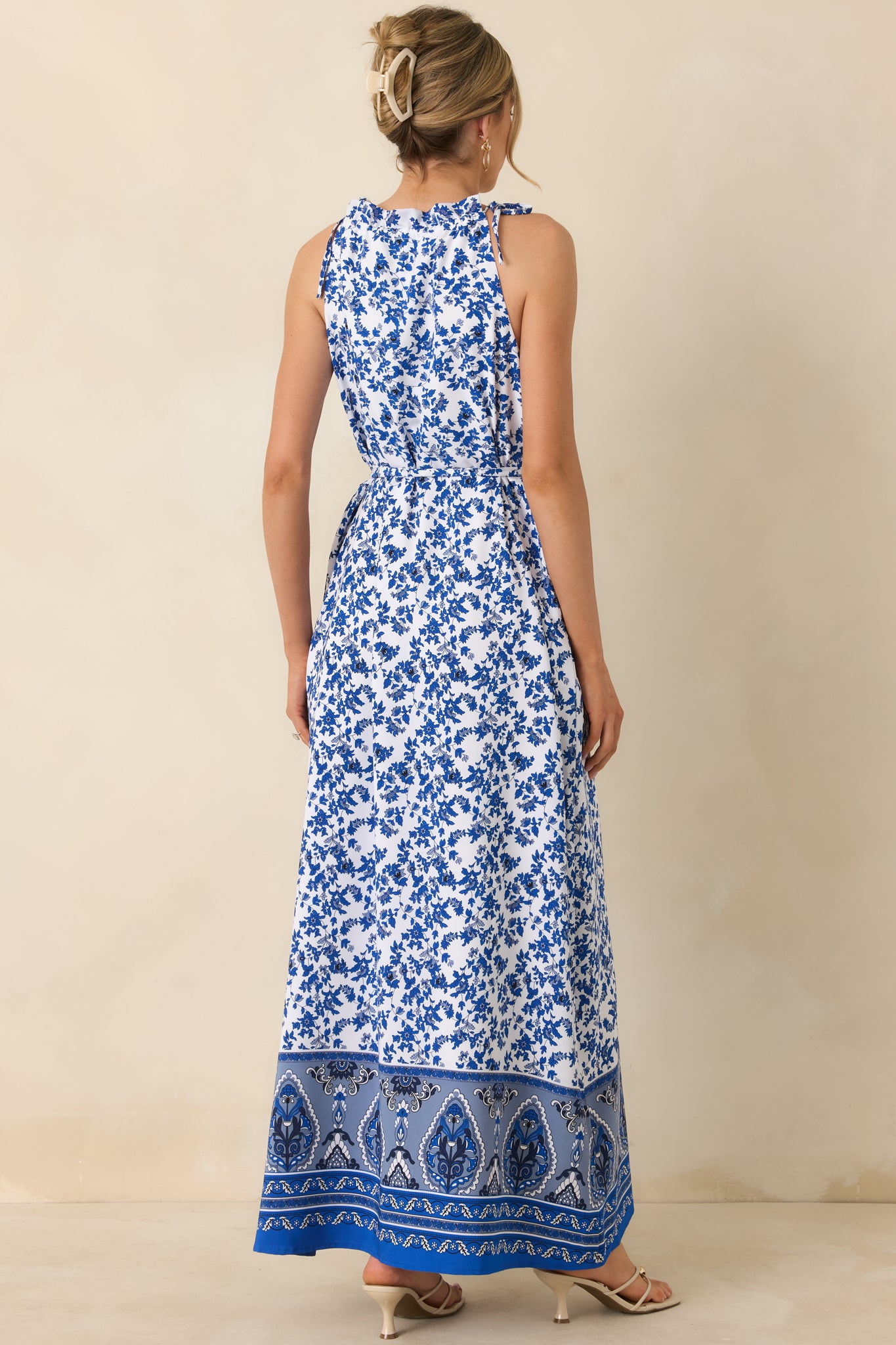 Back view of blue floral dress displaying self-tie straps, belt loops, and flowing skirt silhouette.