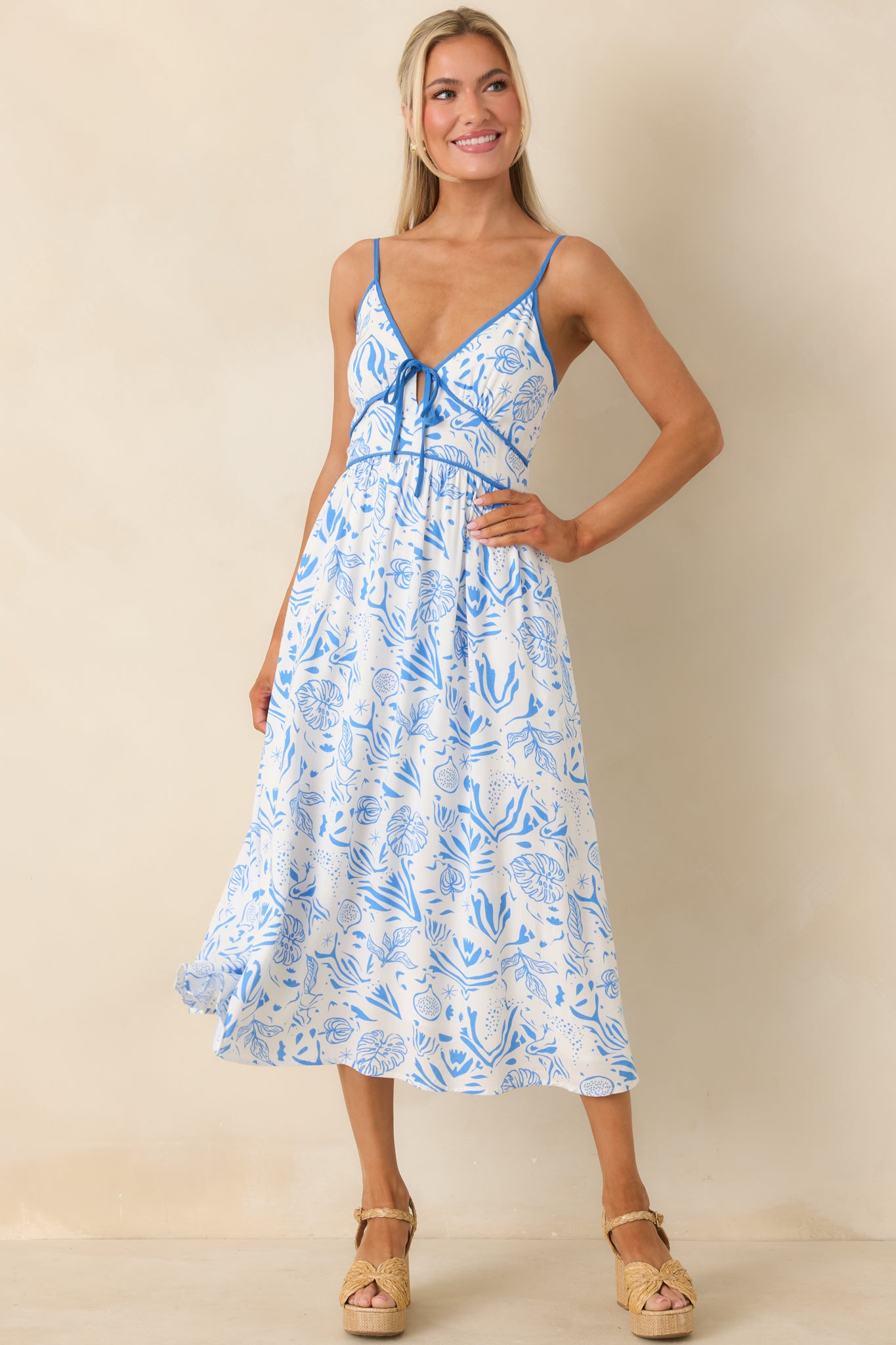 Blue tropical-print midi dress with V-neckline, adjustable spaghetti straps, and smocked back panel.