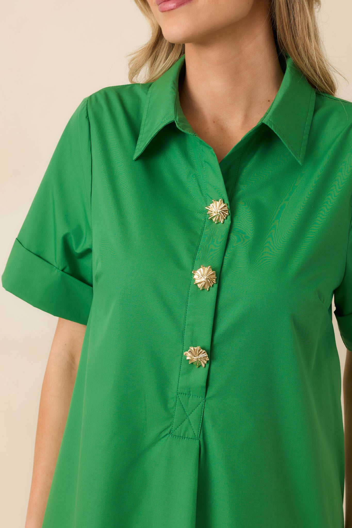 Close-up of the green maxi dress showing the collared neckline and statement gold-tone buttons along the placket.