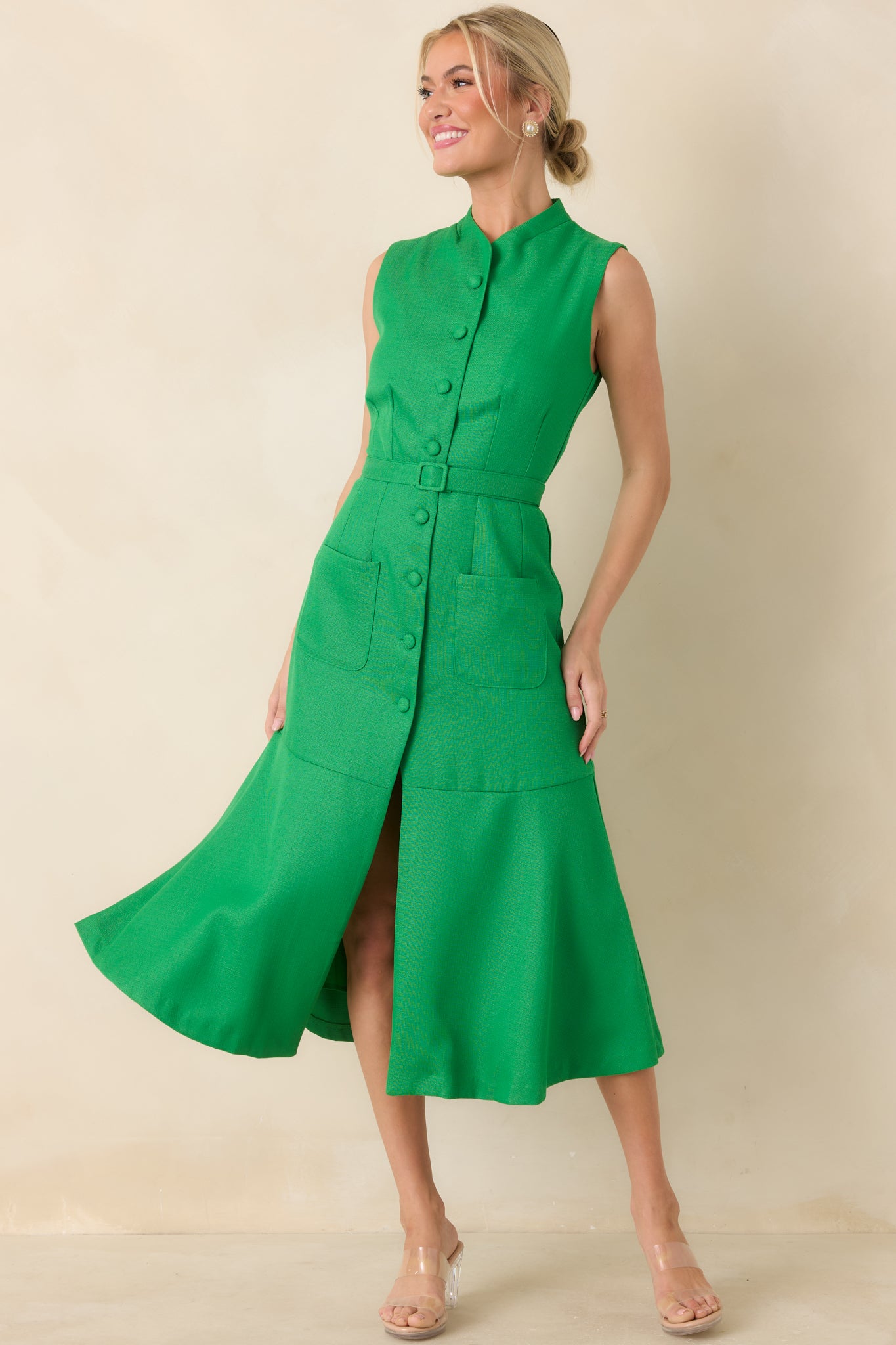 Vivid green midi dress featuring a stand collar, covered button front, vertical seam shaping, coordinating waist belt, patch pockets, and a softly flared skirt.