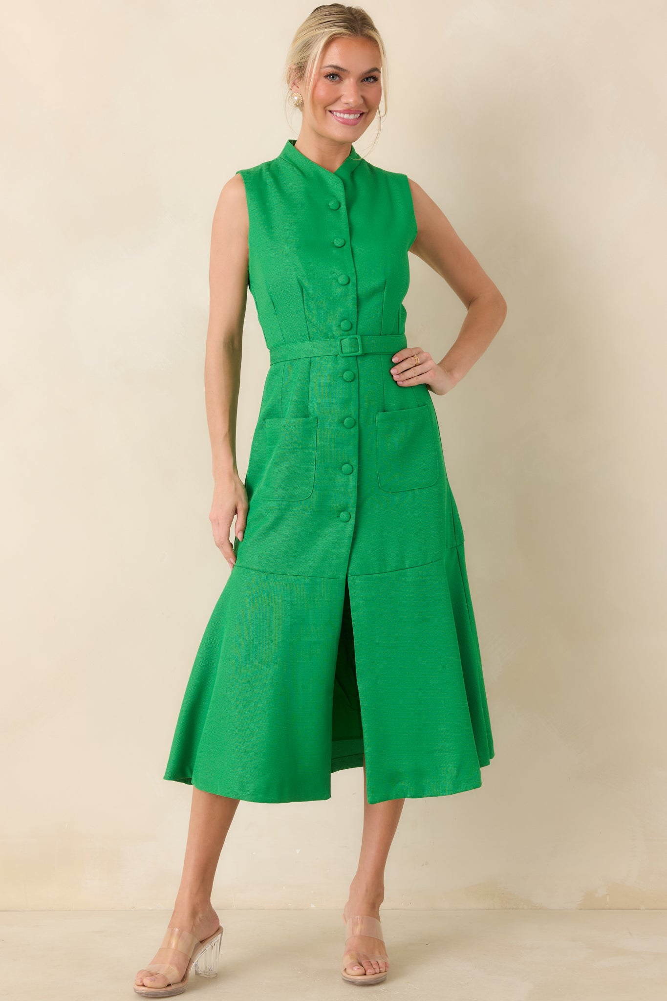 Polished green midi featuring a structured stand collar, row of covered buttons, vertical seam detailing along the bodice, waist-defining belt, and a flowing skirt.
