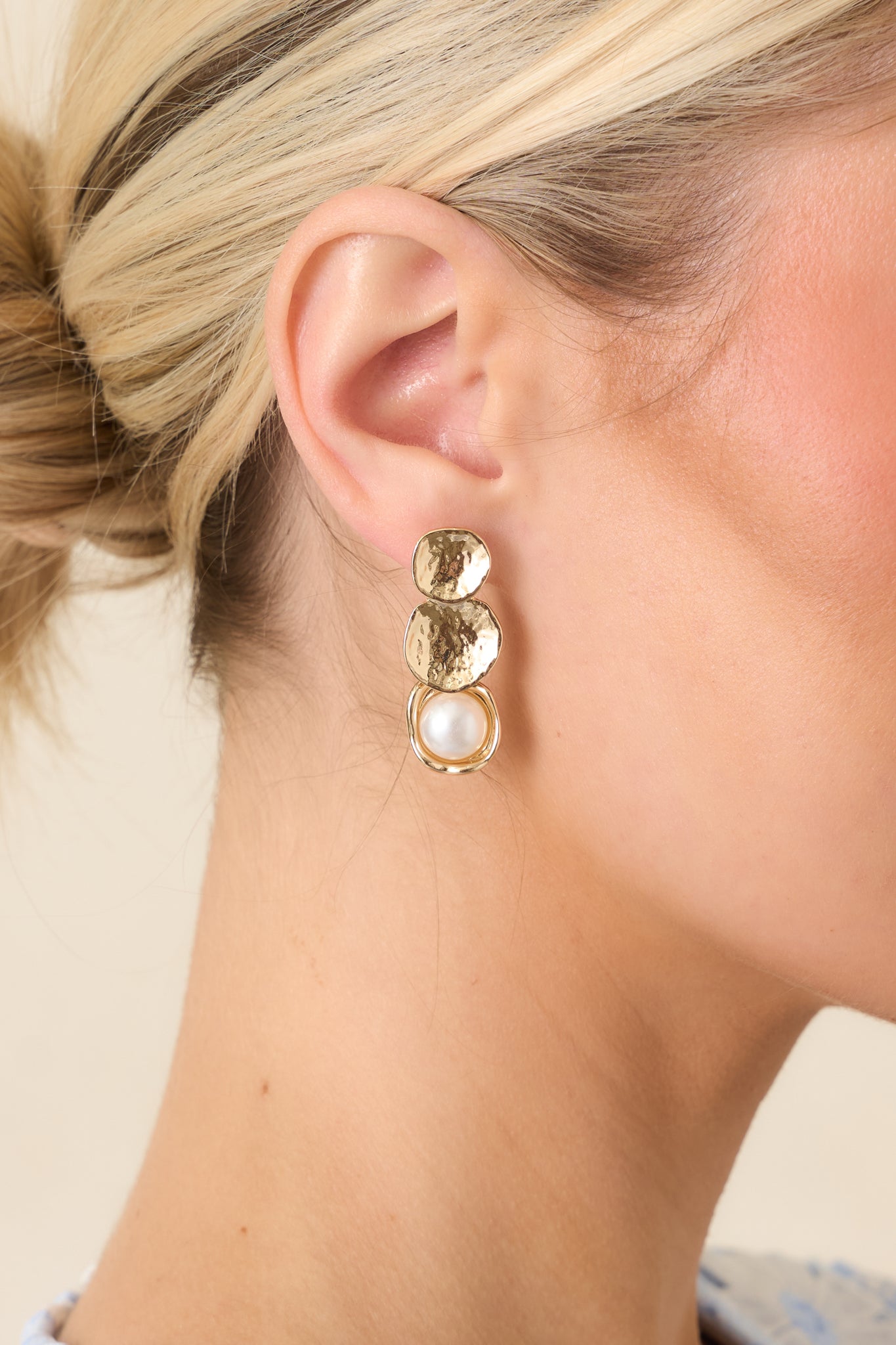 Close-up of gold disc and framed pearl earrings emphasizing the textured finish, layered silhouette, and polished pearl detail.