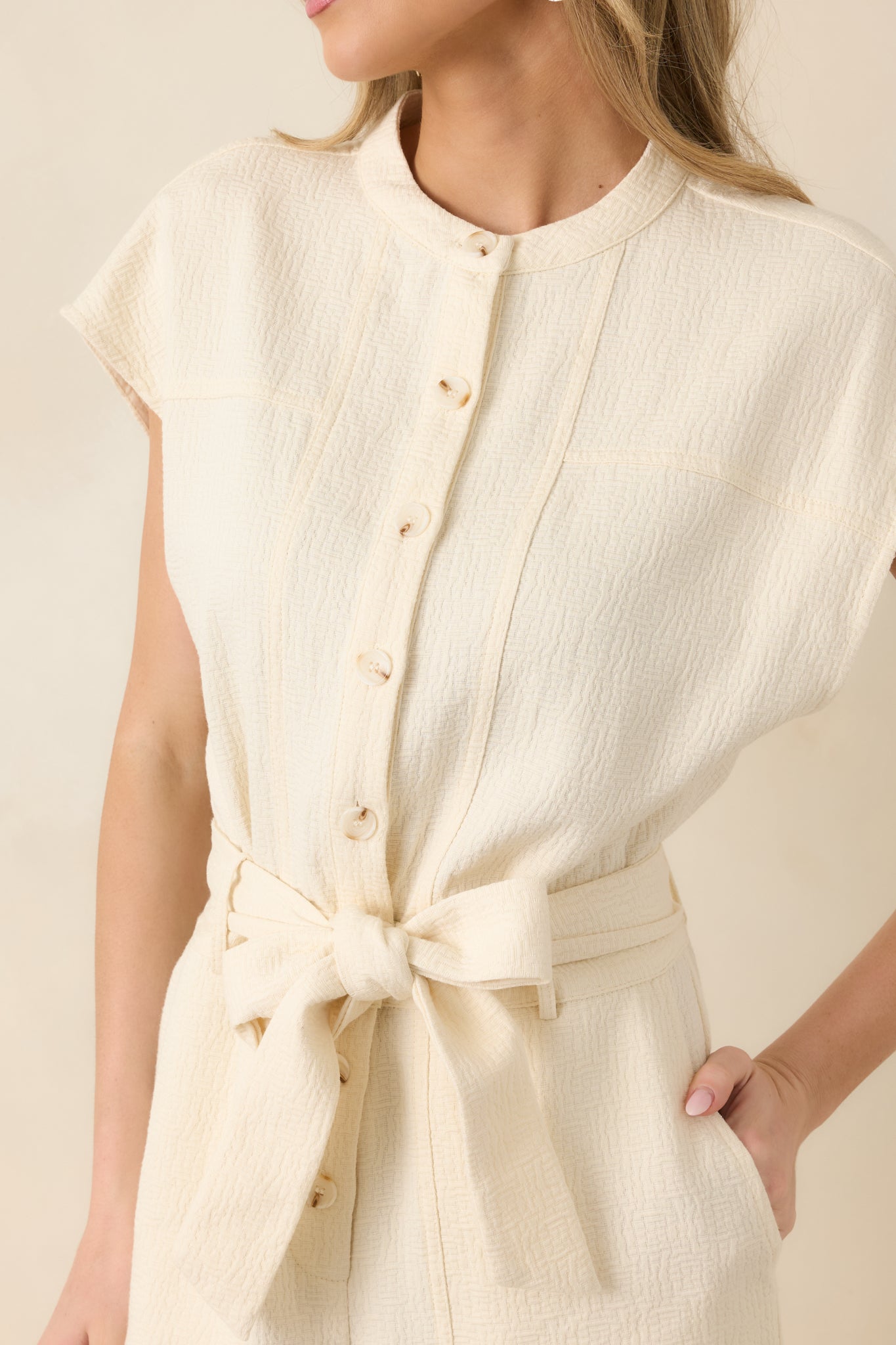 Close-up of button-front closure, round neckline, self-tie belt, and lightweight woven fabric texture.