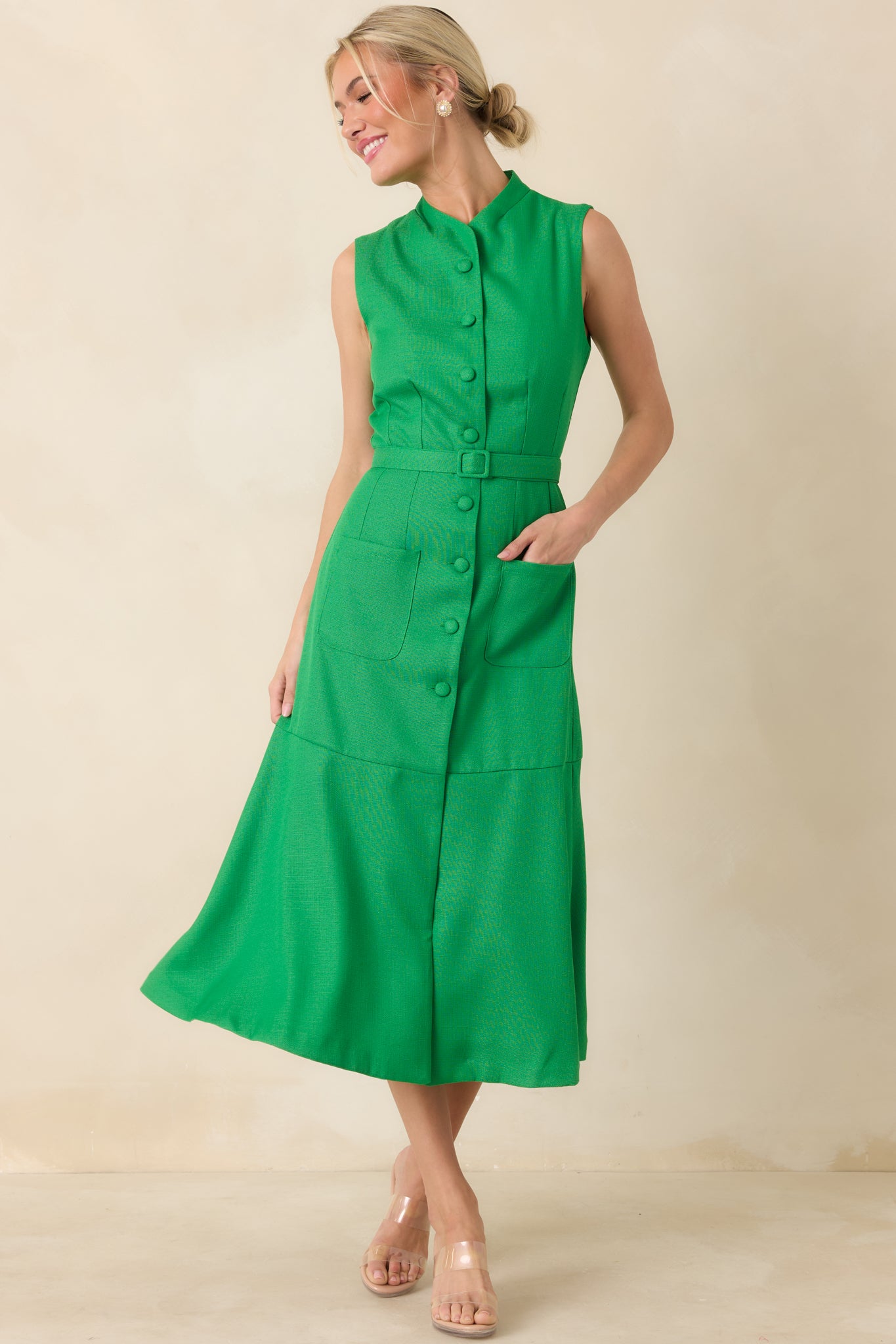 Elegant green midi dress with vertical seam shaping, a stand collar, covered front buttons, coordinating waist belt, and a softly flared skirt that moves easily.