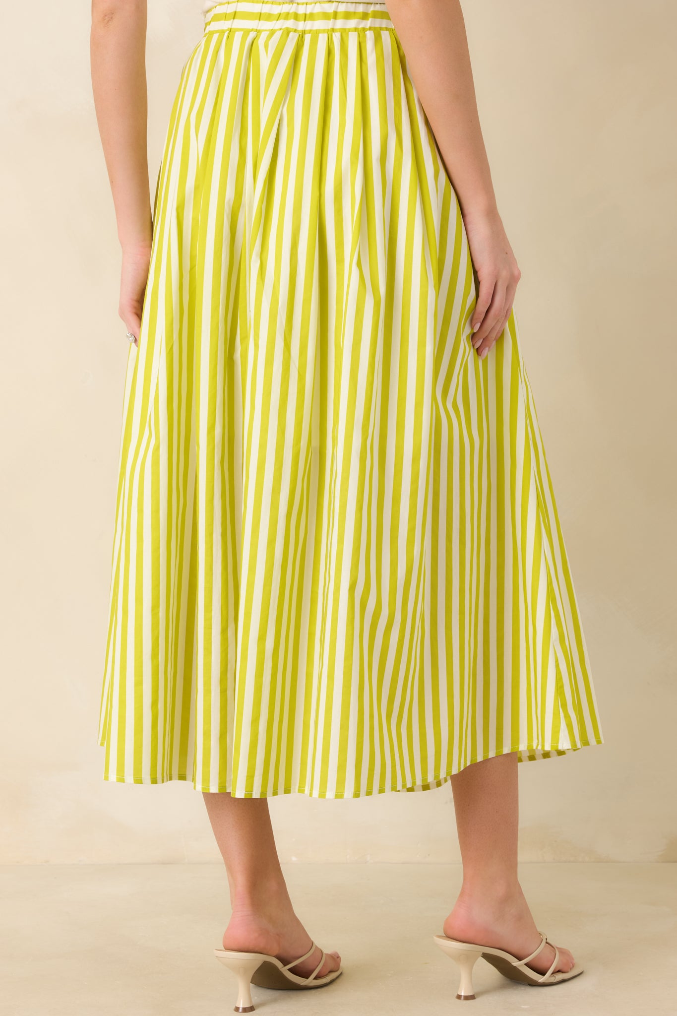 Back view of the green high-waisted maxi skirt featuring elastic waistband and continuous vertical stripe pattern.