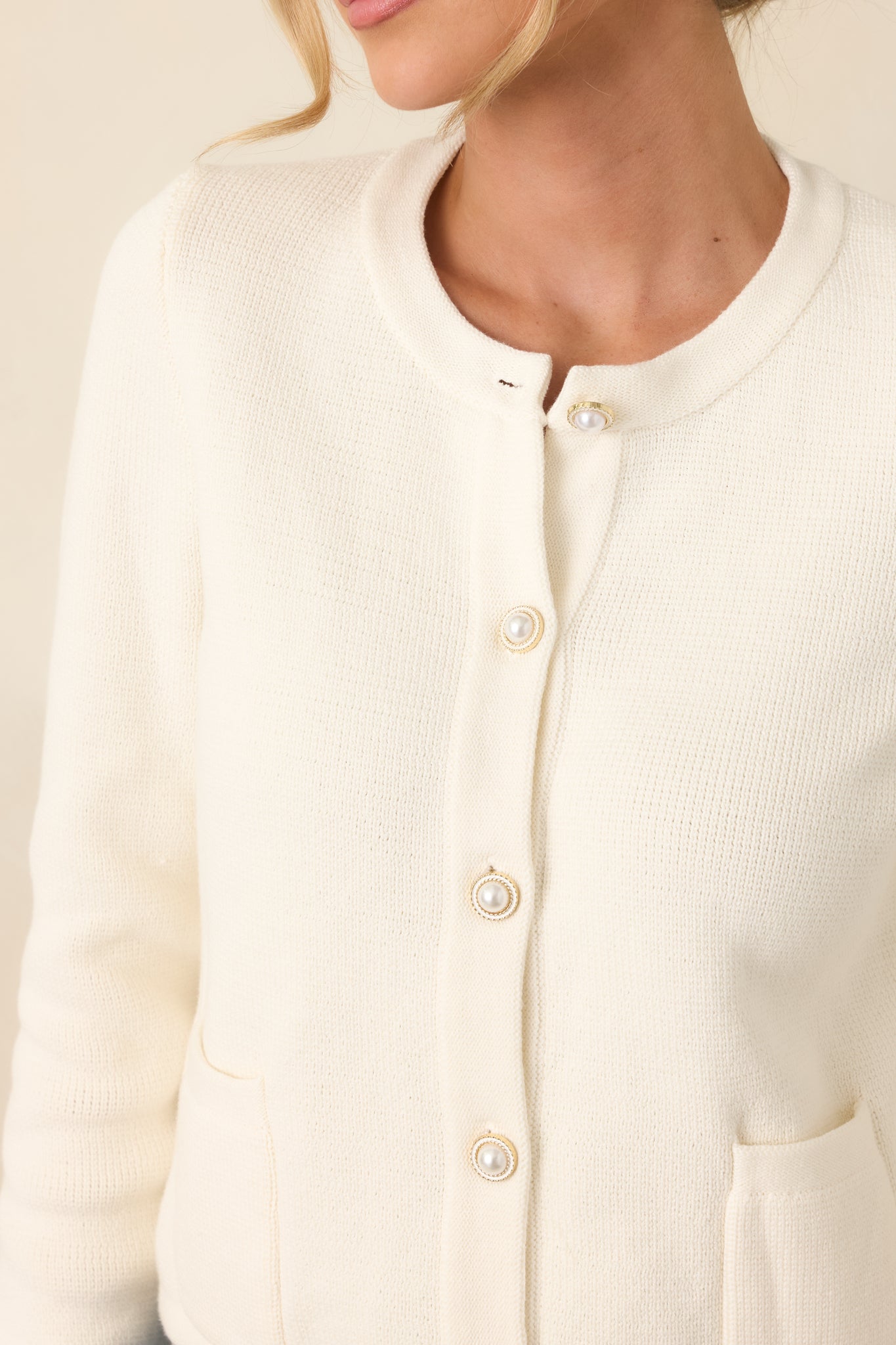 Close-up of faux pearl button and finely woven cotton knit texture.