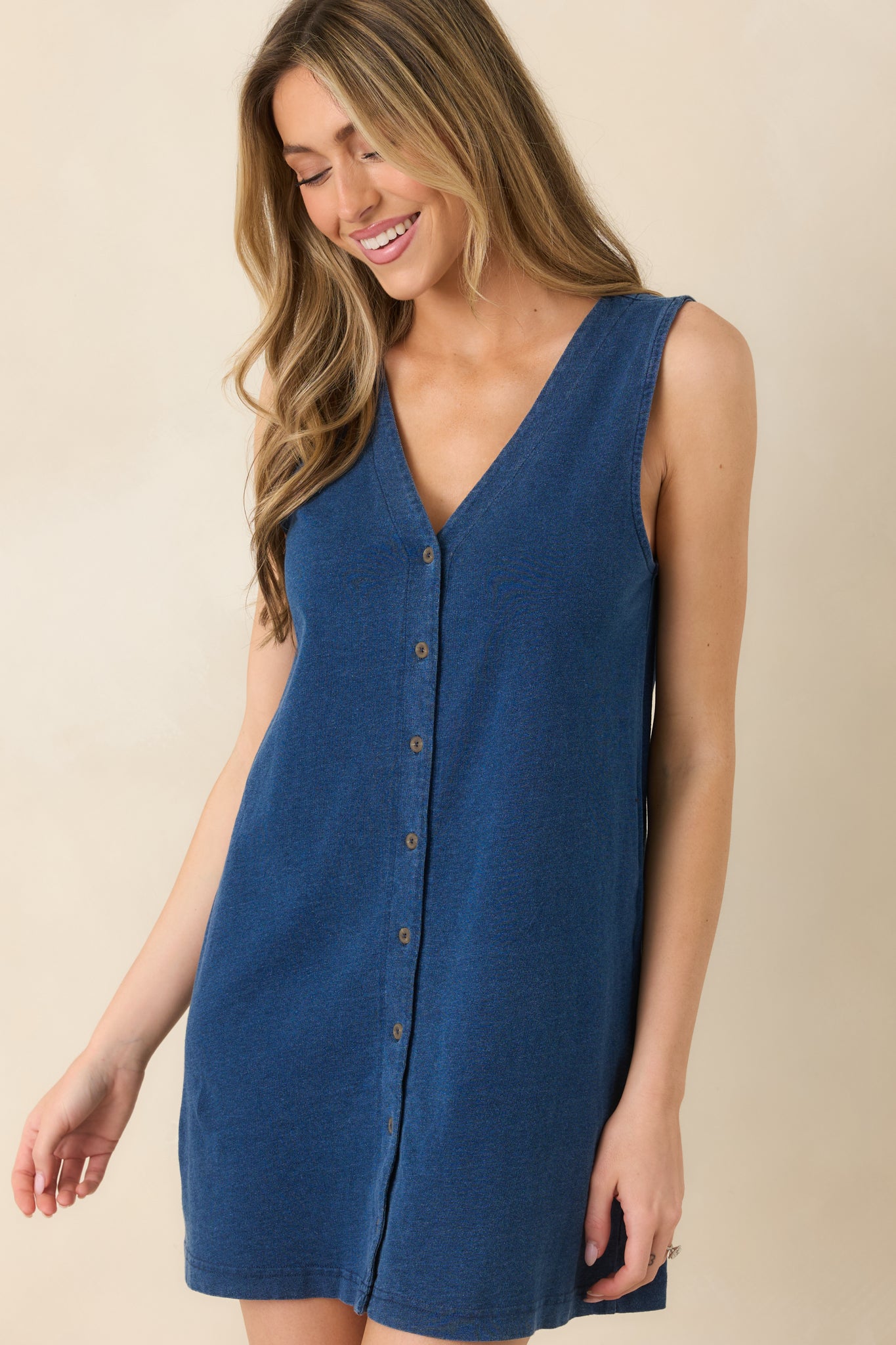 Cropped detail of sleeveless mini dress highlighting rich dark wash and front buttons.