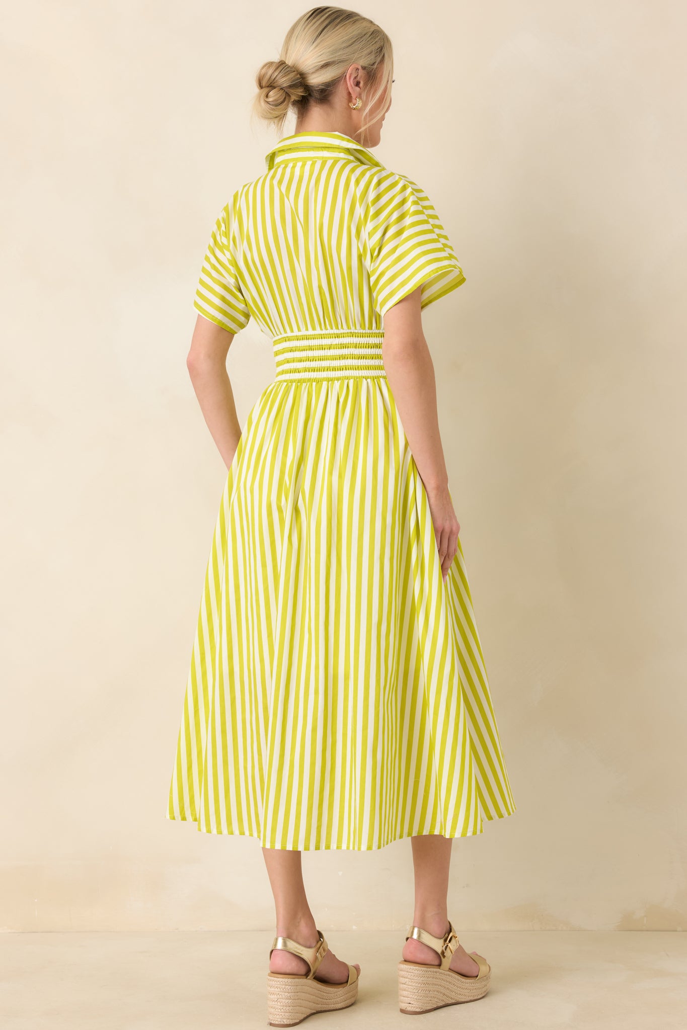Rear view of the green and white striped midi dress highlighting the smocked waistband, short sleeves, and gently flared A-line skirt.