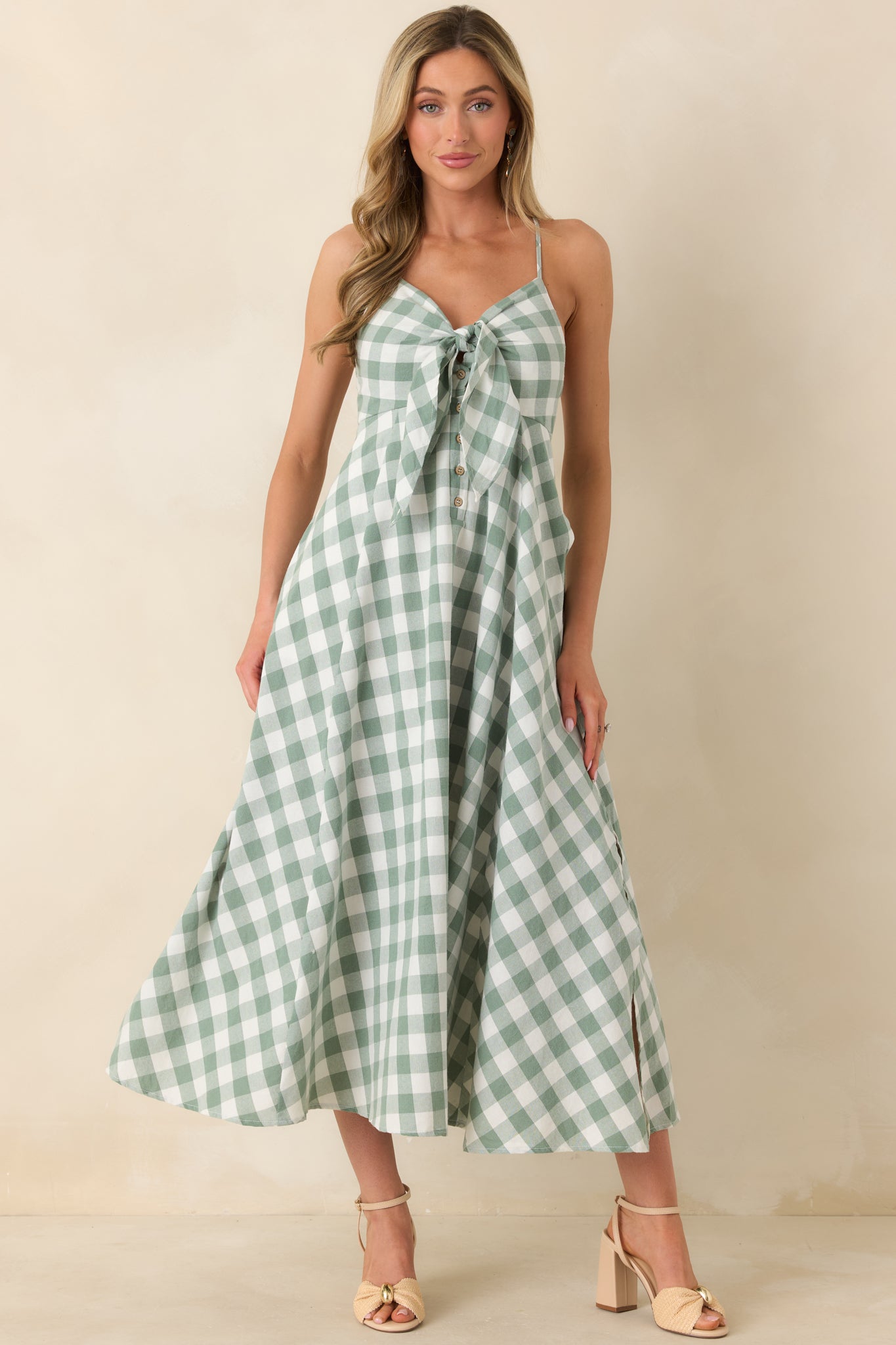 Chic midi silhouette with a V-neck front tie accent, classic button details, and a softly sweeping skirt that creates gentle movement along the hemline.