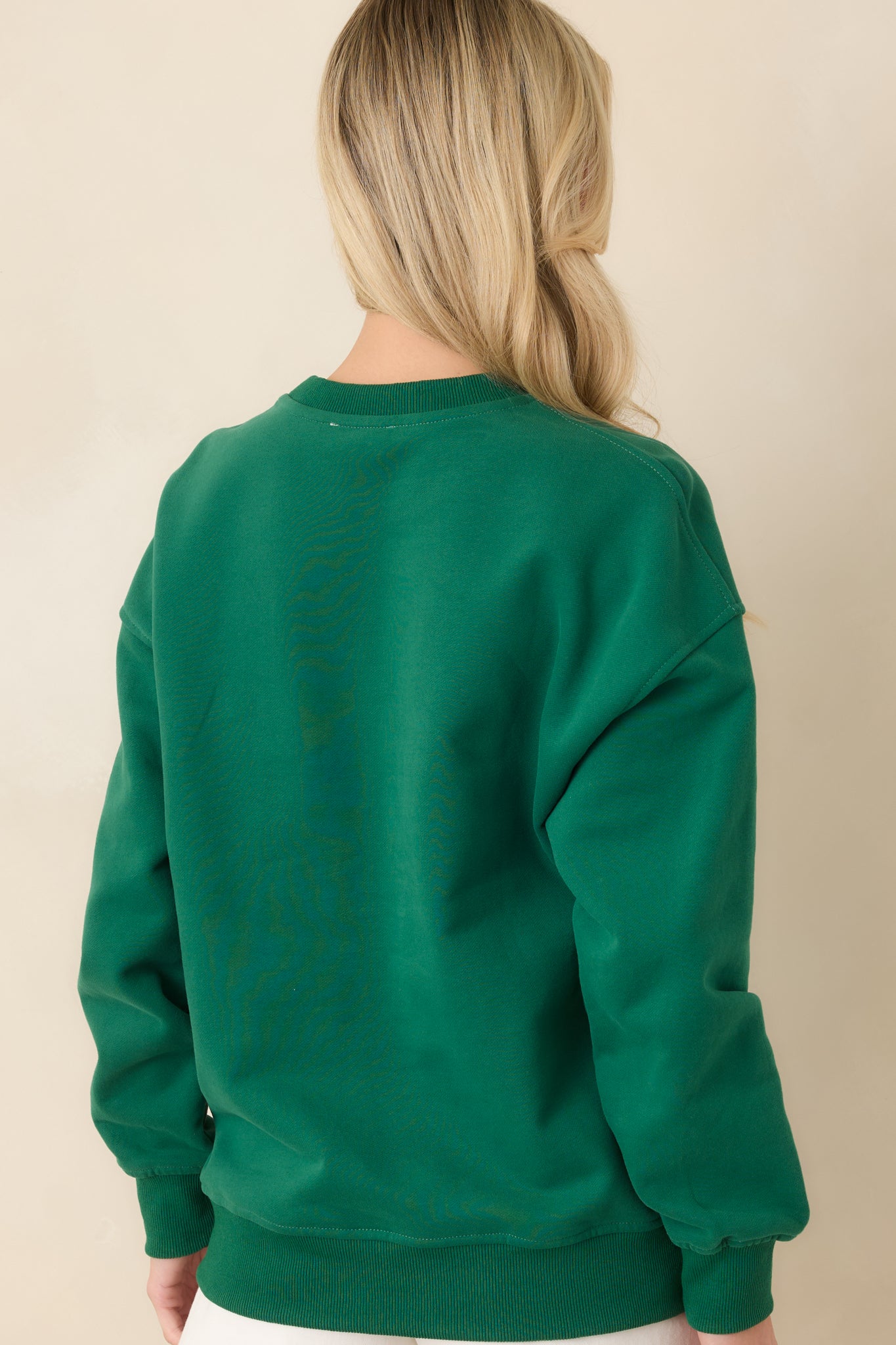 Back view of the forest green sweatshirt showing smooth back panel and ribbed hemline.