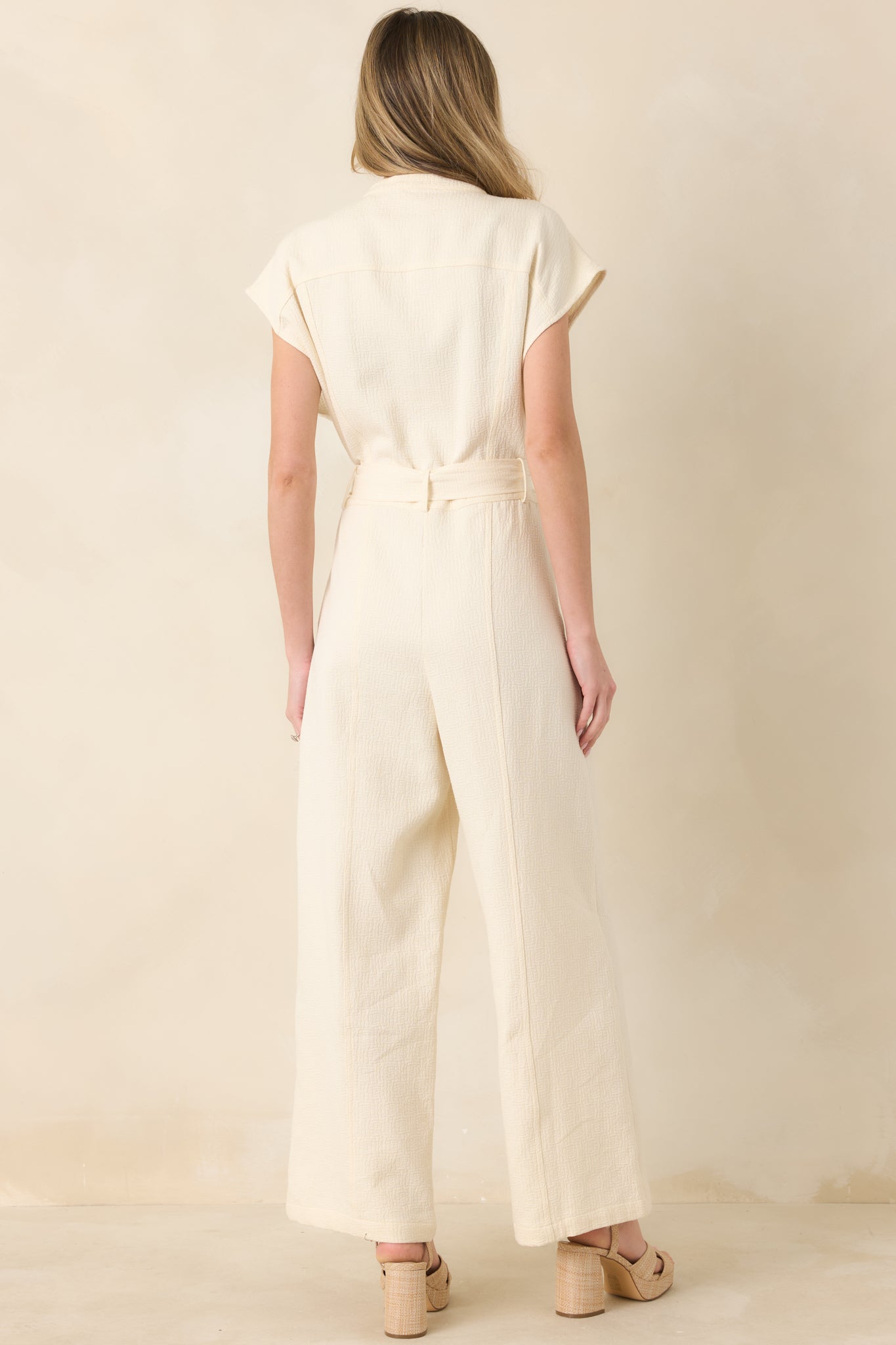 Back view of jumpsuit showing relaxed fit, wide-leg silhouette, and clean back detailing with subtle cap sleeves.