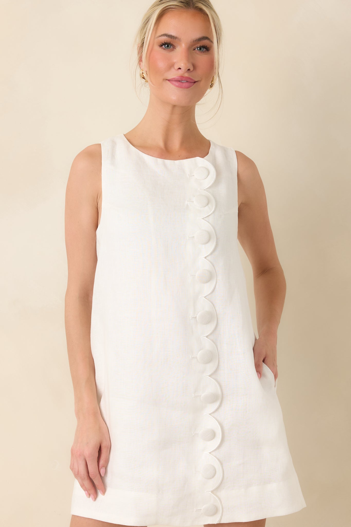Sleeveless white dress featuring front scalloped design and easy drape