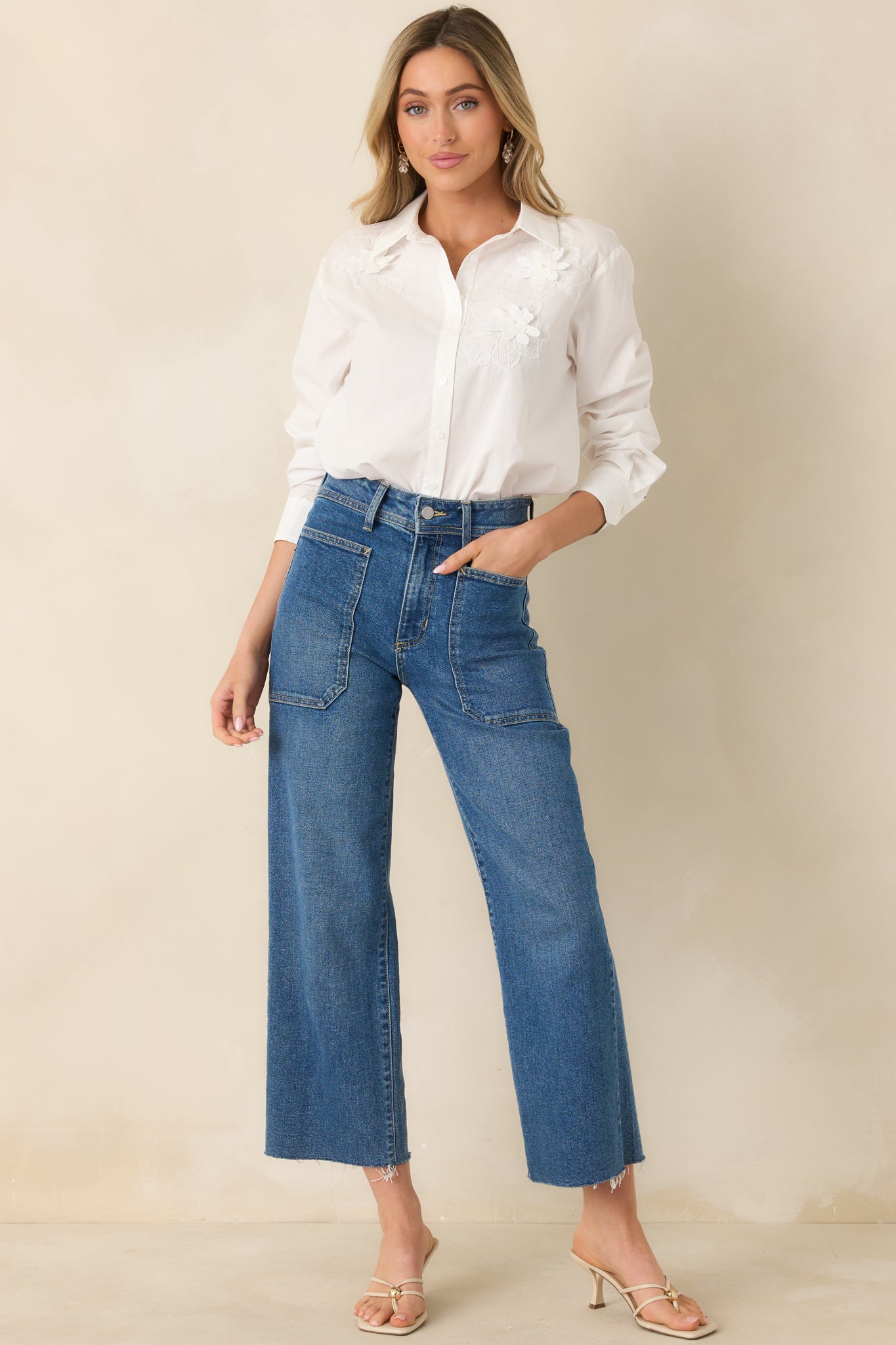 Front-facing white woven blouse showcasing a full button placket, floral detailing, and a versatile silhouette for tucked or untucked styling.