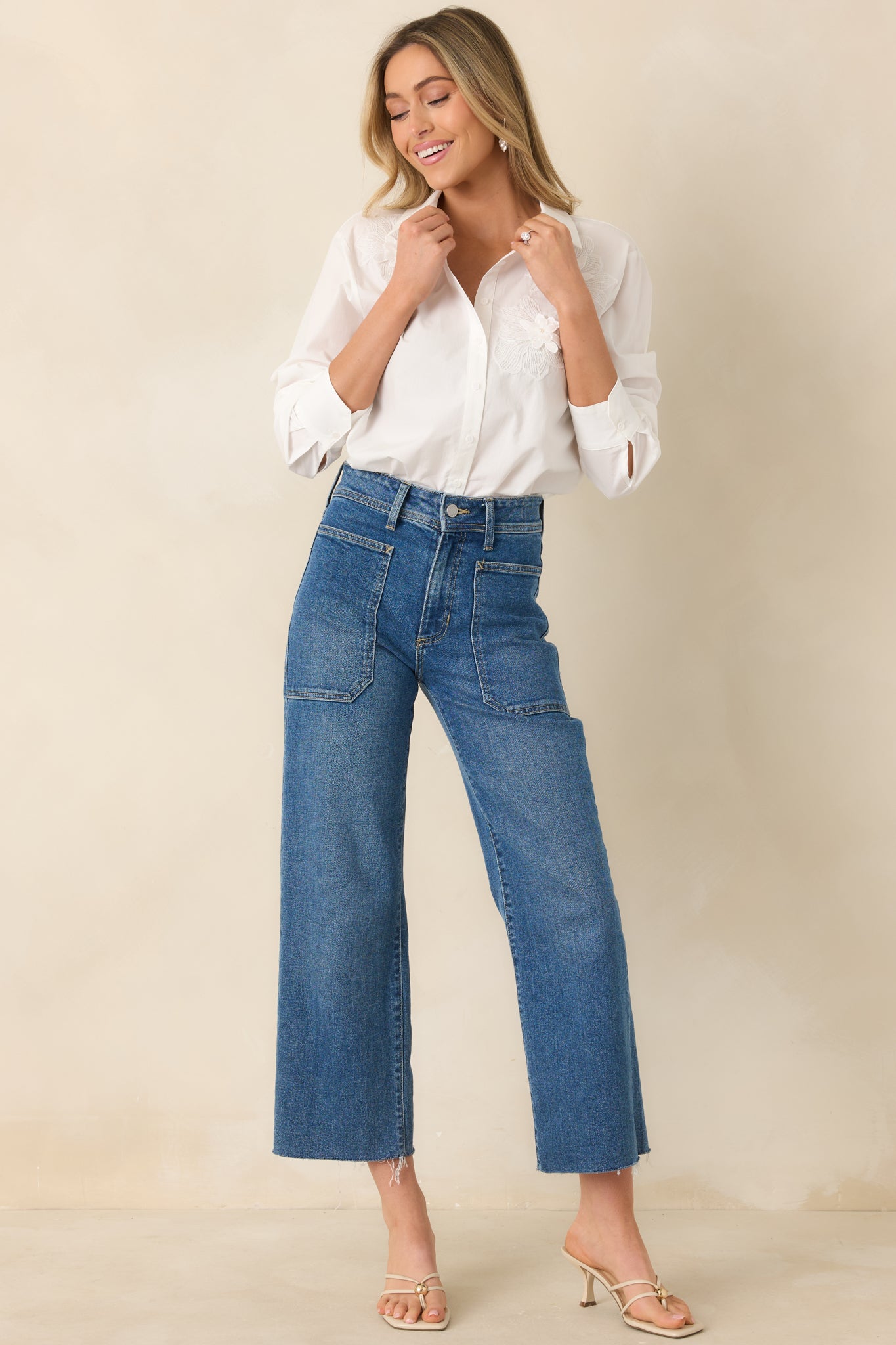 White button-up blouse with a classic collared neckline, long sleeves with button cuffs, and floral appliqué details along the front.
