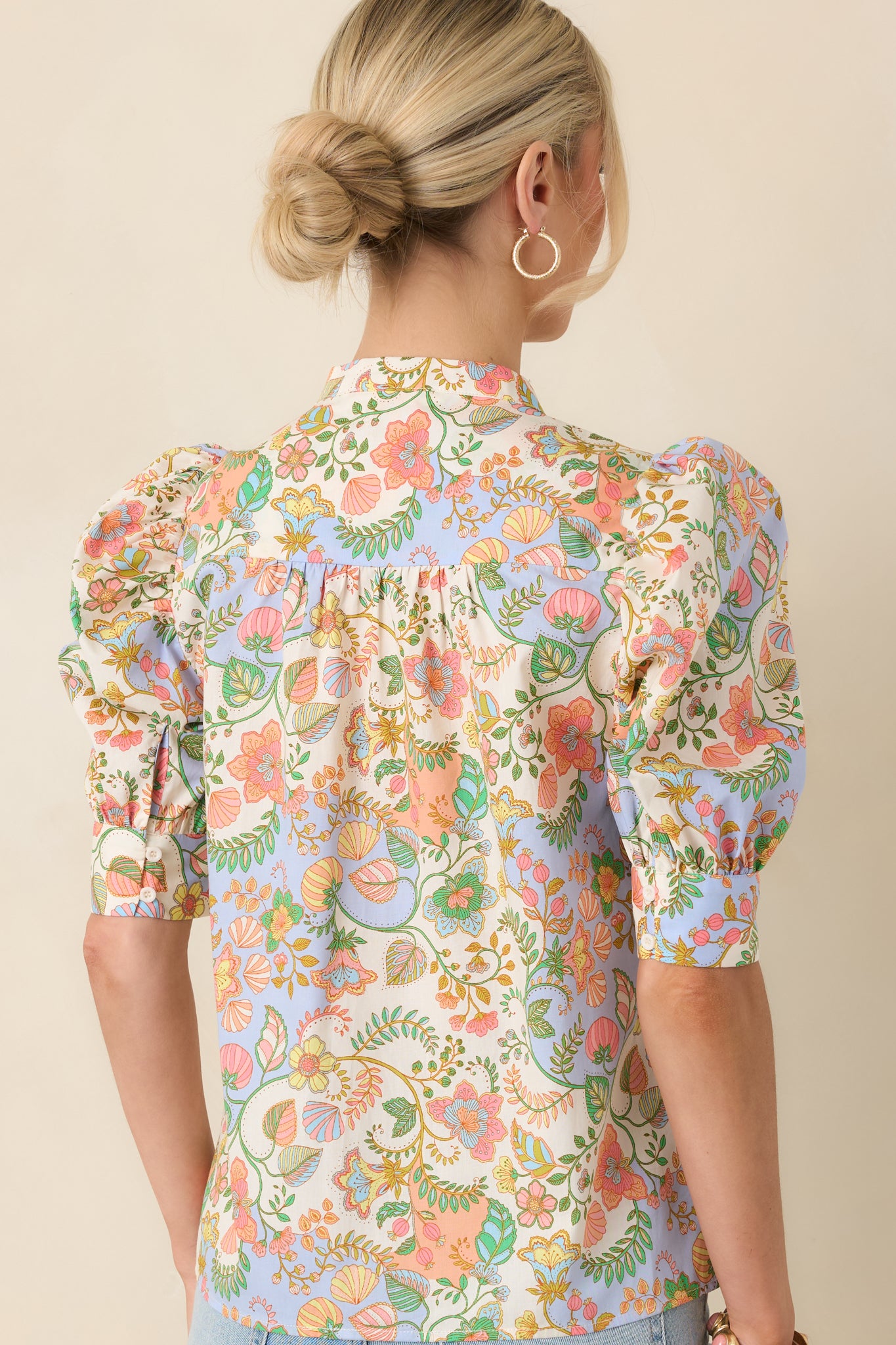 Rear view of the cotton blouse displaying the clean silhouette and full puff sleeves with structured cuffs from behind.