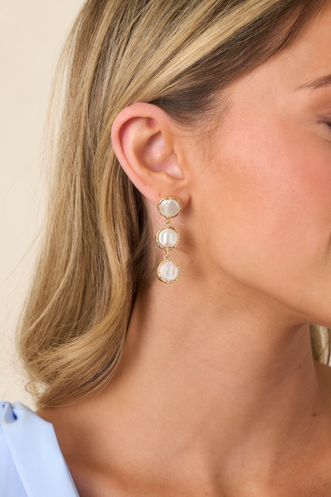 Side view of drop earrings emphasizing vertical pearl arrangement and smooth gold framing.