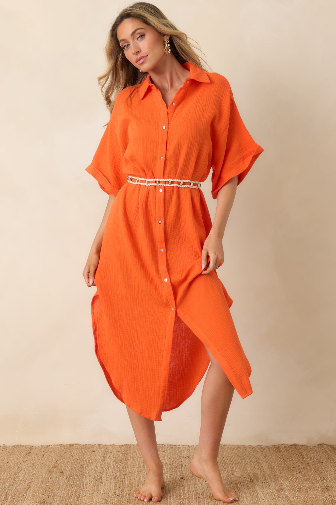 Button-front midi dress with woven belt, flowing skirt, and bright orange cotton fabric.