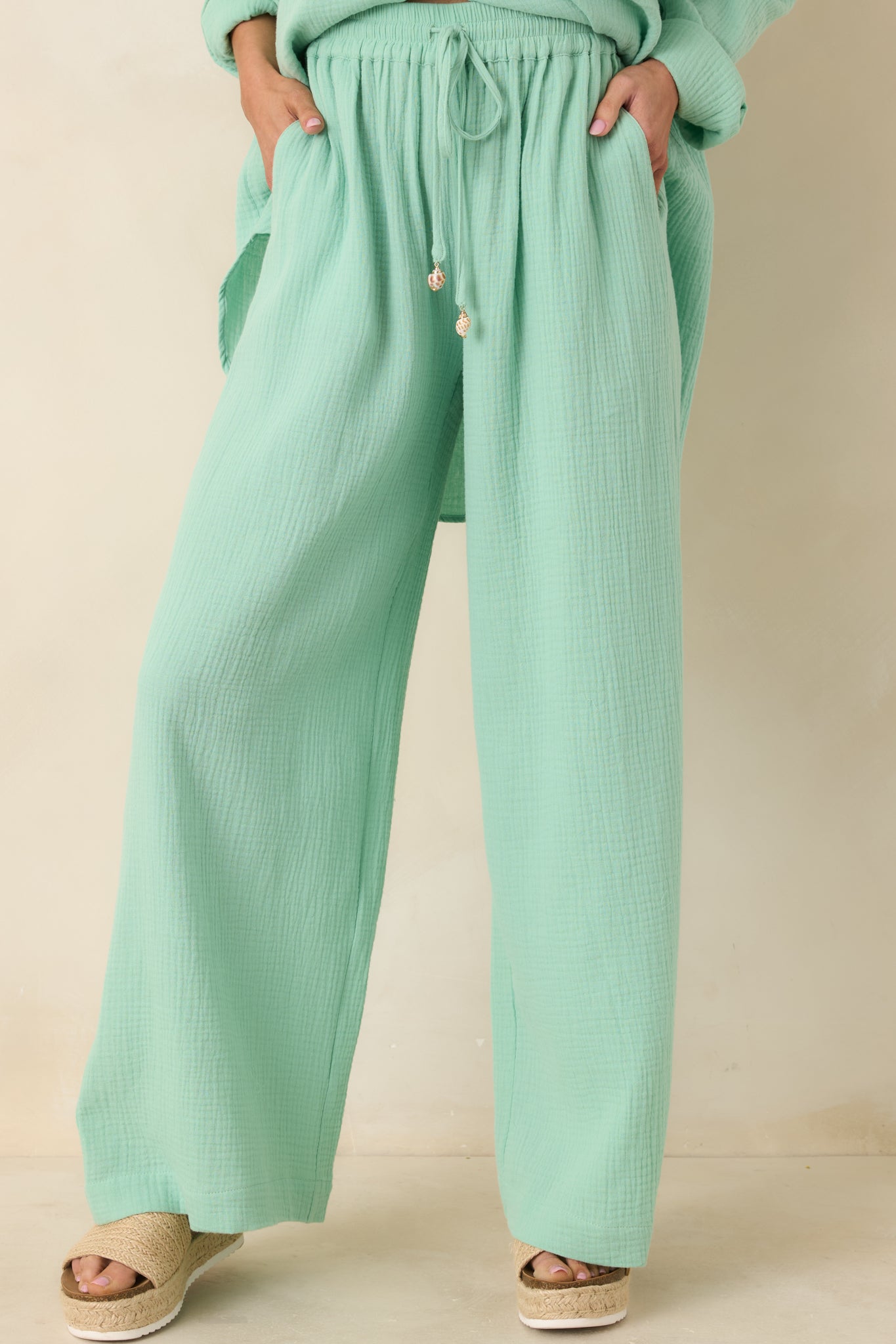 Side pocket detail on airy seafoam green cotton pants with soft, flowy drape.