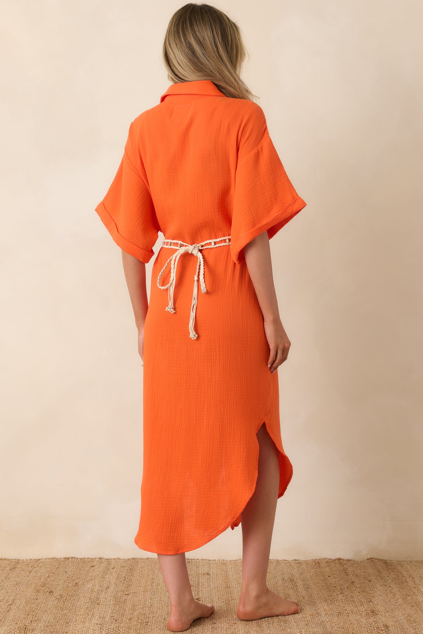 Rear view of the orange midi dress with relaxed sleeves, removable belt, and soft curved hem.