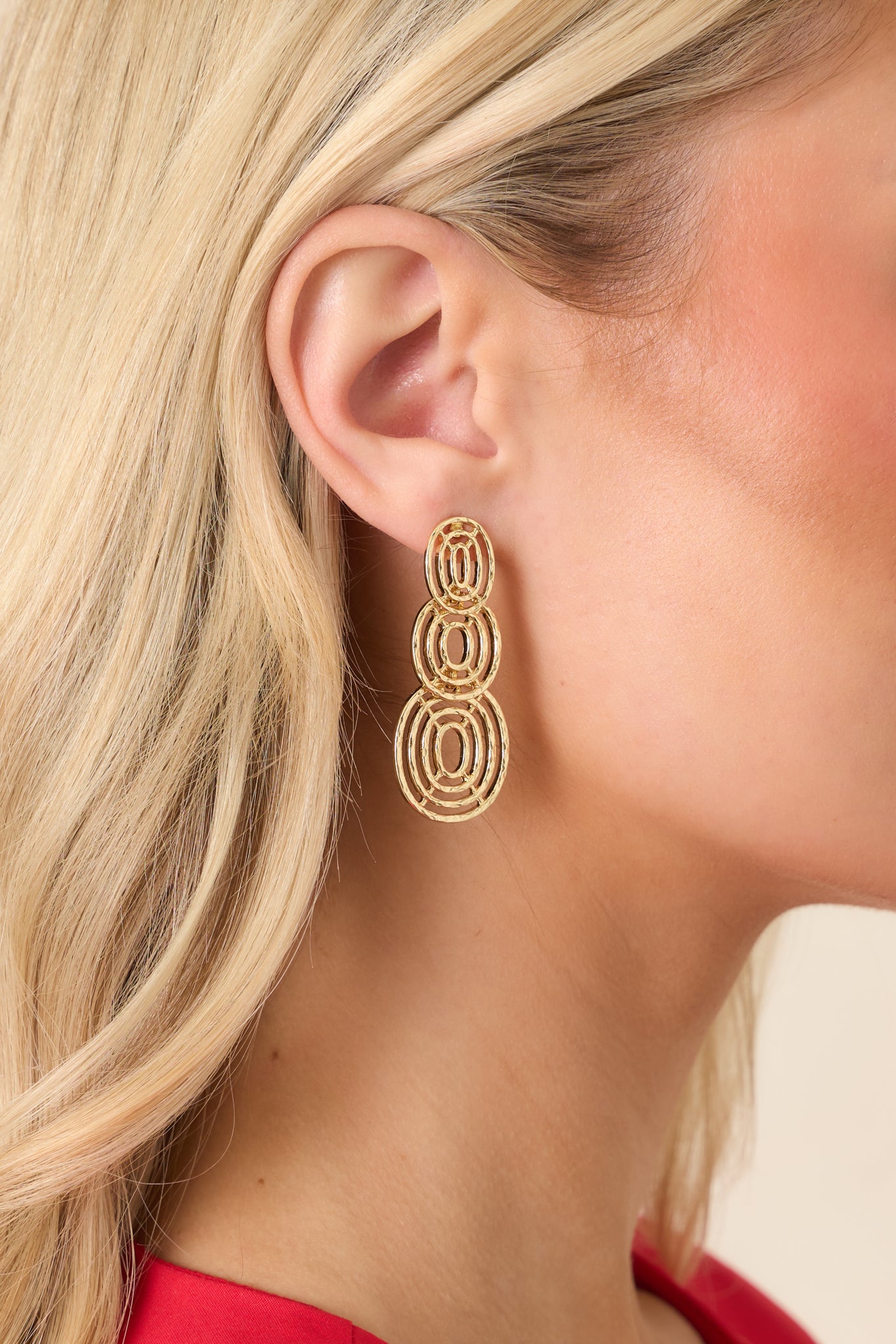Layered gold-tone hoop earrings with three interconnected circular drops for a sleek, contemporary look.